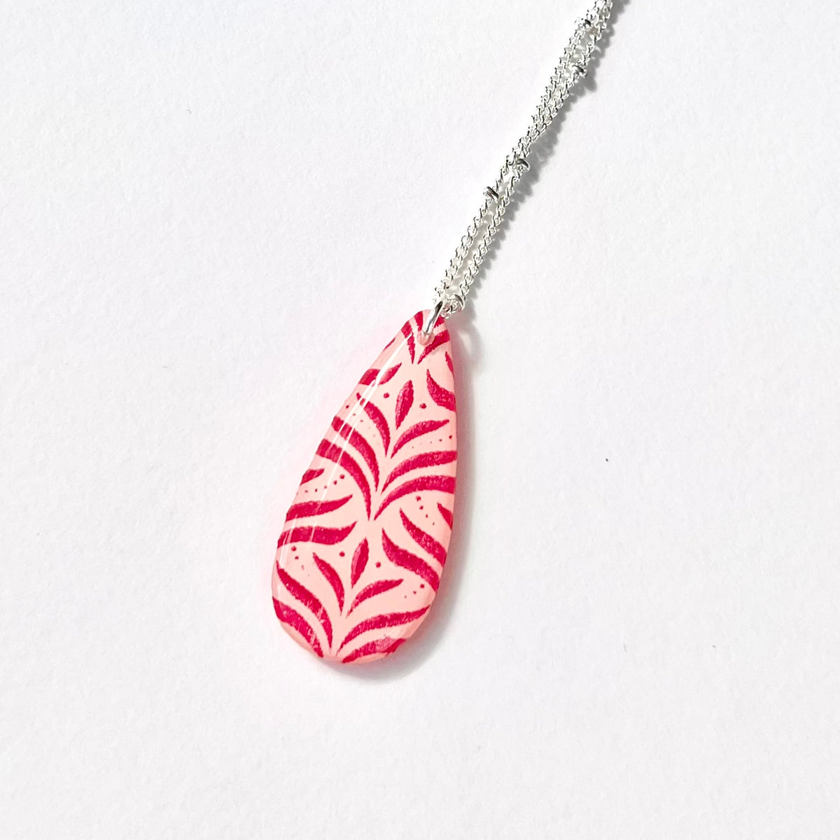 Close-up of pink and red hand-painted botanical resin-coated pendant