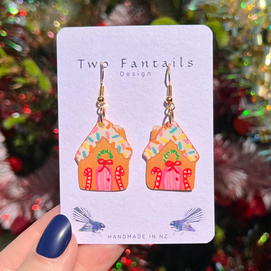 Colourful gingerbread house earrings with a sprinkle-covered roof, wreath and candy cane details