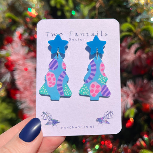 Bright blue star studs and hand-painted blue Christmas trees with pink, purple and mint abstract patterns