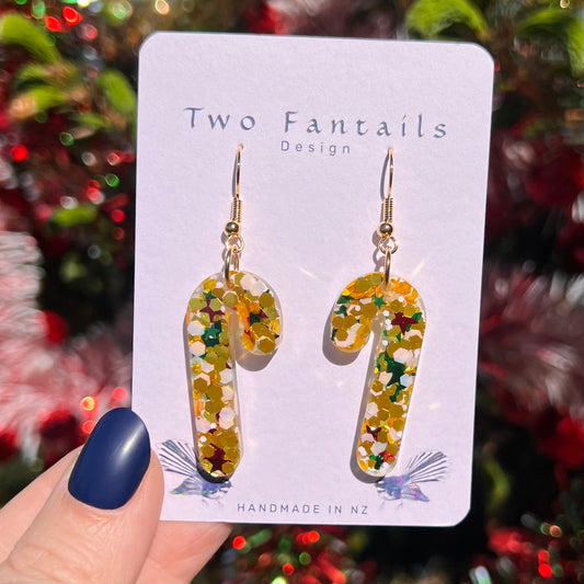 Clear candy cane earrings filled with golden glitter, white confetti and red and green stars, finished with gold-tone hooks