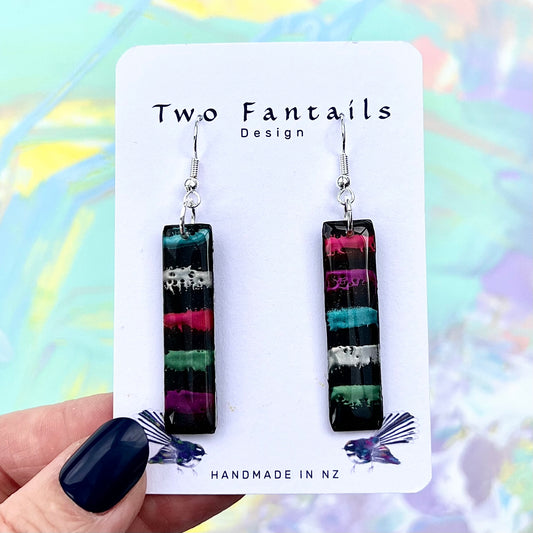 Black rectangular drop earrings with colourful hand-painted drip stripes in pink teal white green and purple