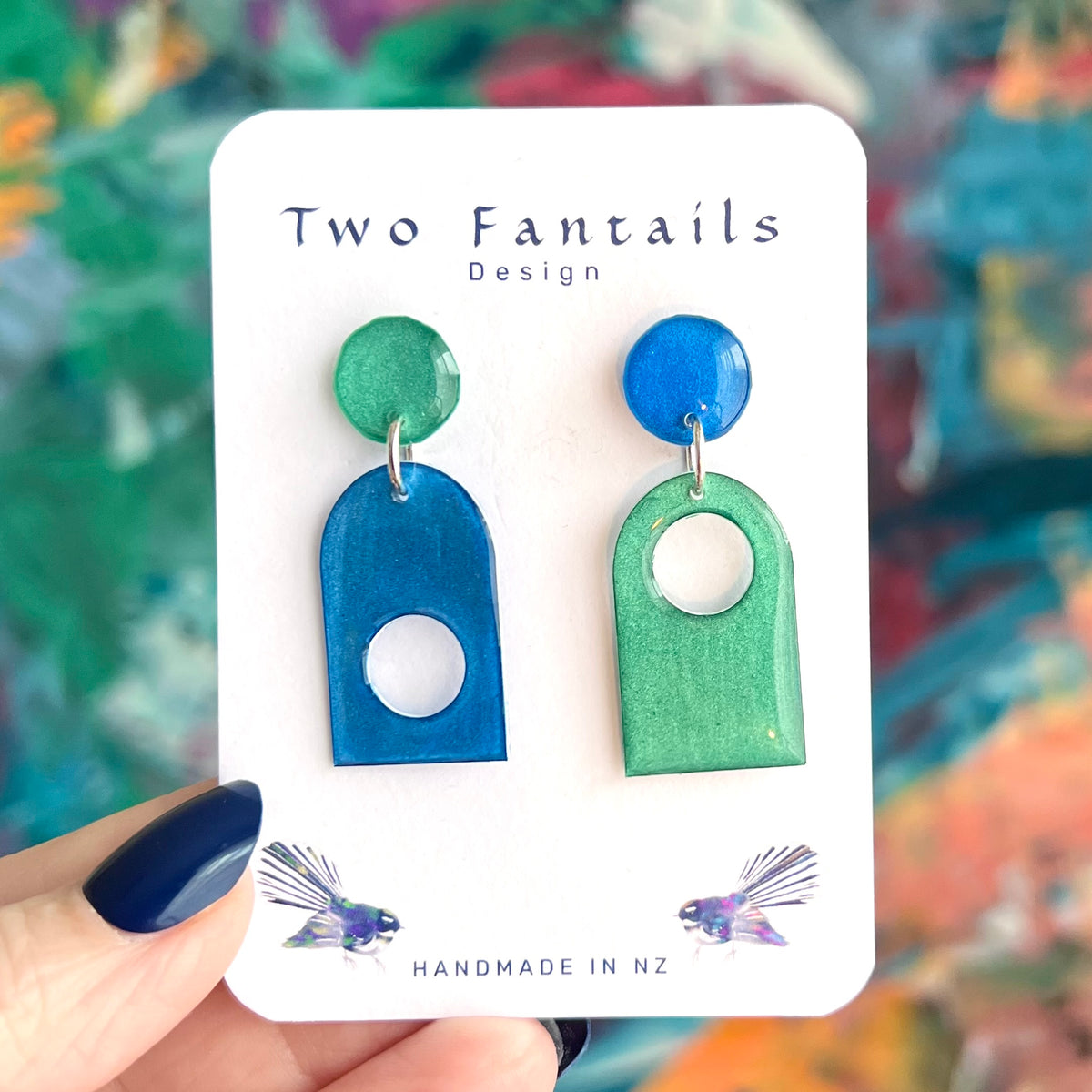 Mismatched metallic cobalt blue and mint green arch dangle earrings with circular cutouts and contrasting round stud tops, Two Fantails Design