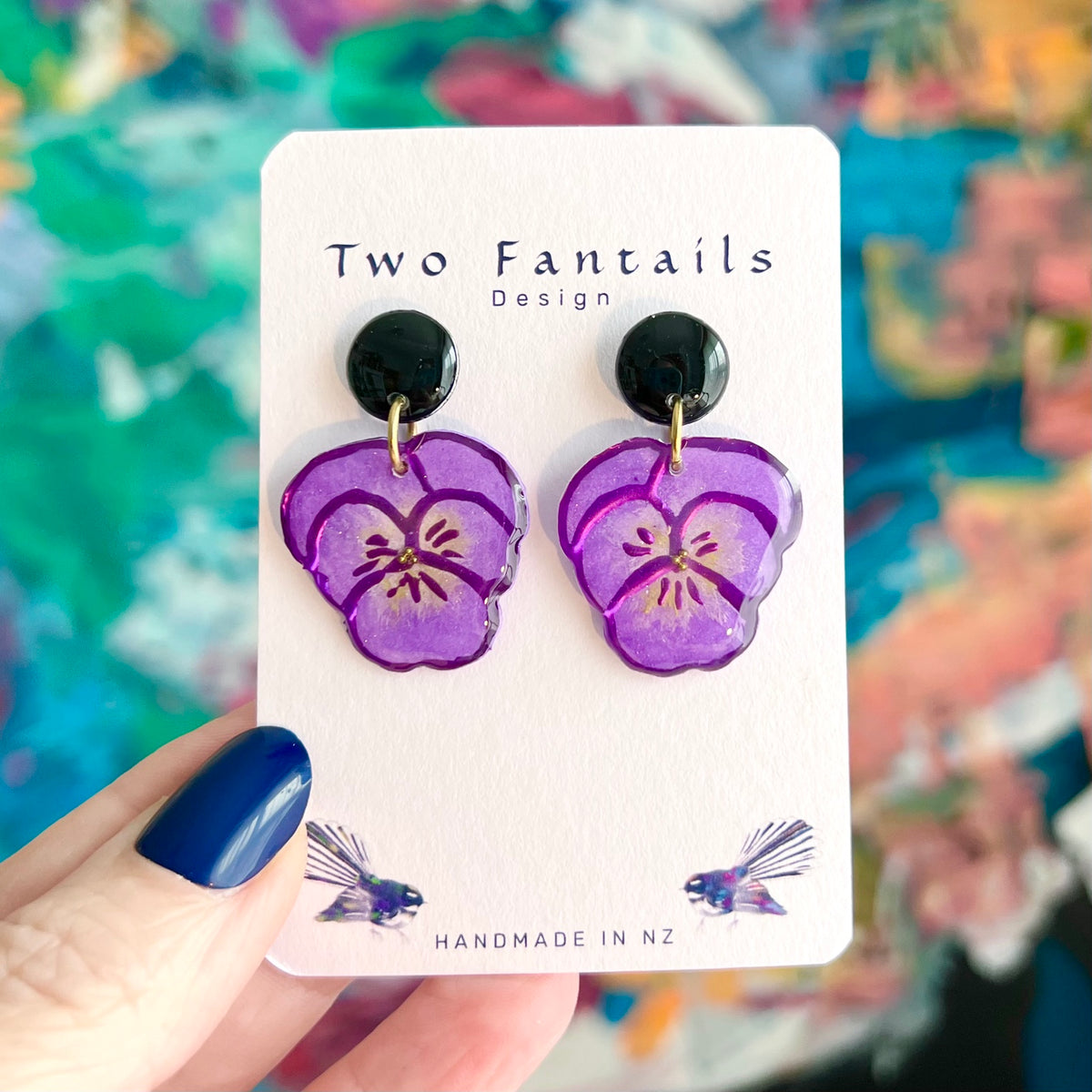 Hand-painted purple pansy flower dangle earrings with glossy black round studs and gold-tone rings by Two Fantails Design