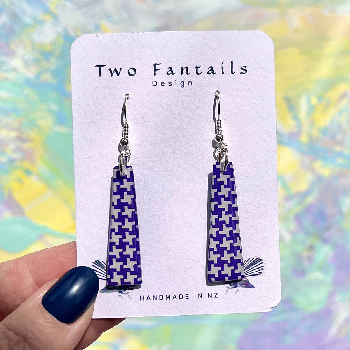 Purple and white geometric patterned long tapered dangle earrings on Two Fantails Design display card